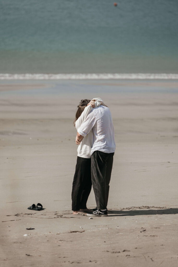 Cooks Beach photographer capturing a surprise proposal as Calvin gets down on one knee with the ocean in the background.