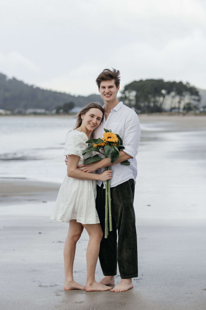 Candid photograph of Chanelle and Calvin embracing right after their proposal at Cooks Beach