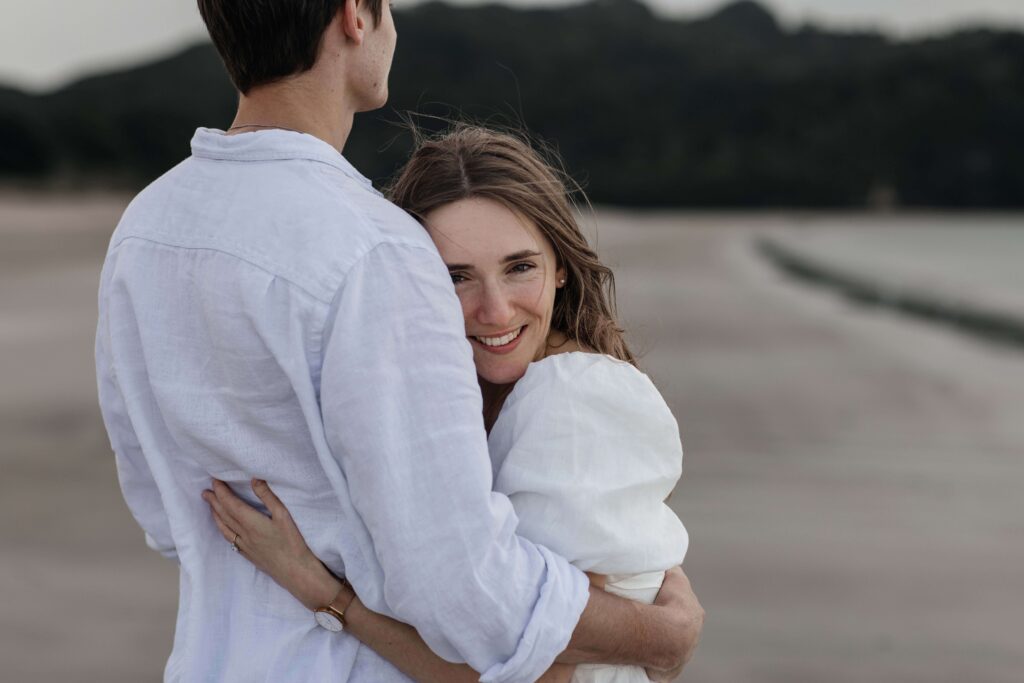 Candid photograph of Chanelle and Calvin embracing right after their proposal at Cooks Beach