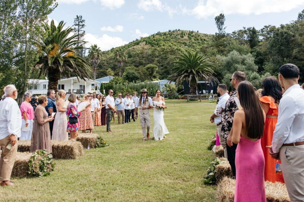 Outdoor Whangamata wedding ceremony with farm backdrop and rolling Coromandel hills.