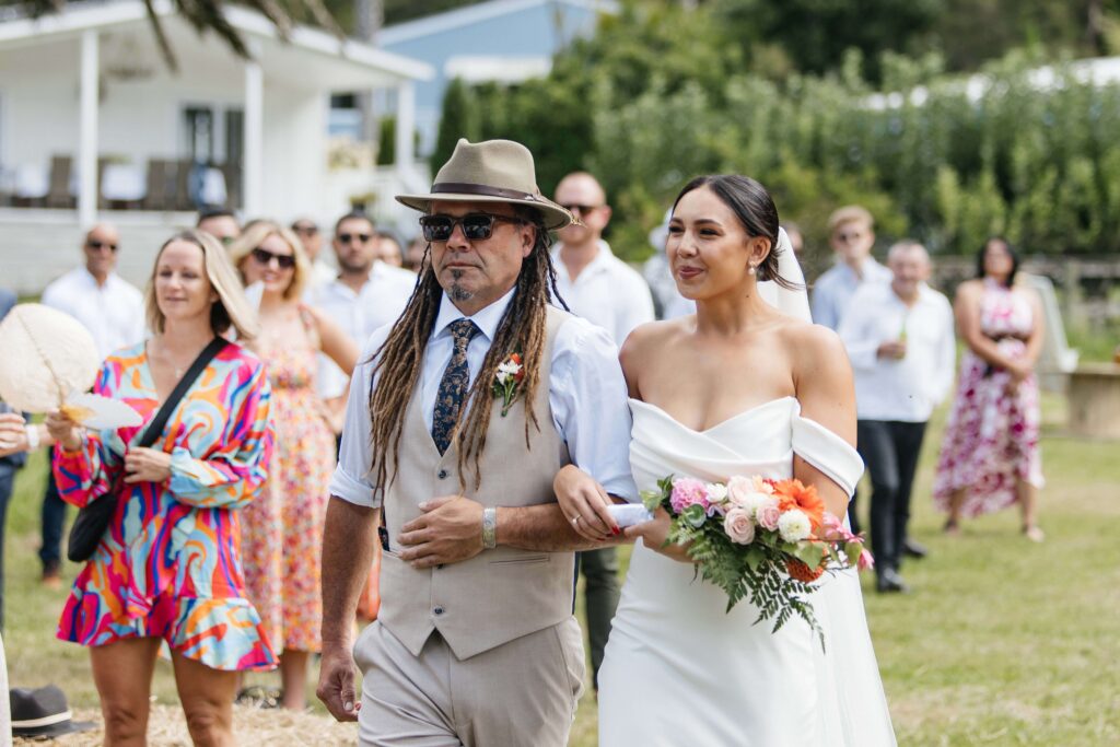 Outdoor Whangamata wedding ceremony with farm backdrop and rolling Coromandel hills.