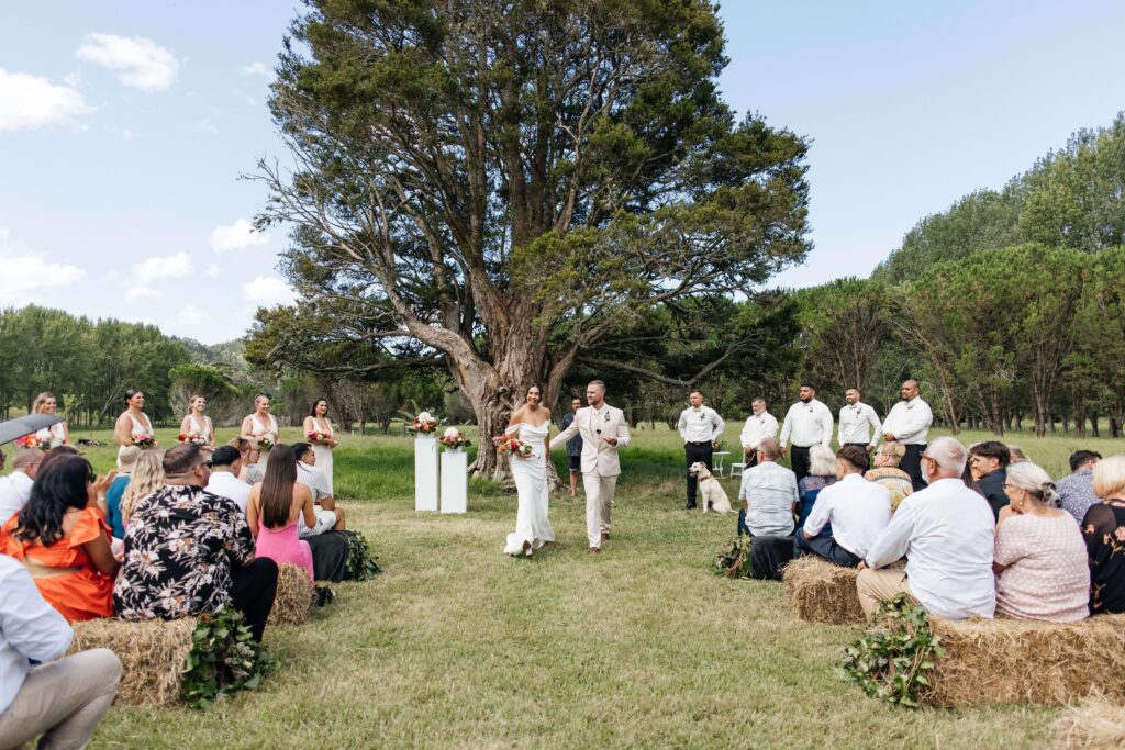 Outdoor Whangamata wedding ceremony with farm backdrop and rolling Coromandel hills.