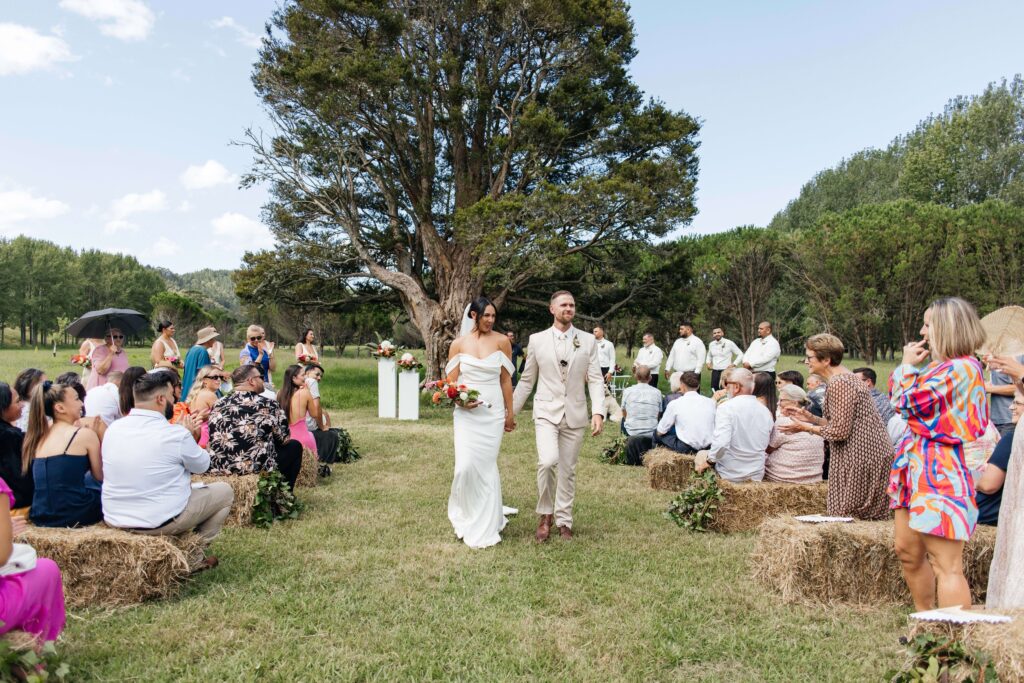 Outdoor Whangamata wedding ceremony with farm backdrop and rolling Coromandel hills.
