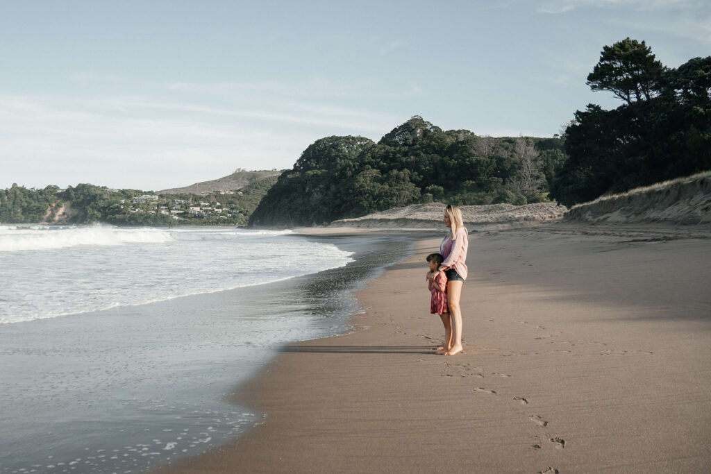 Mother and child walking along Hot Water Beach shoreline