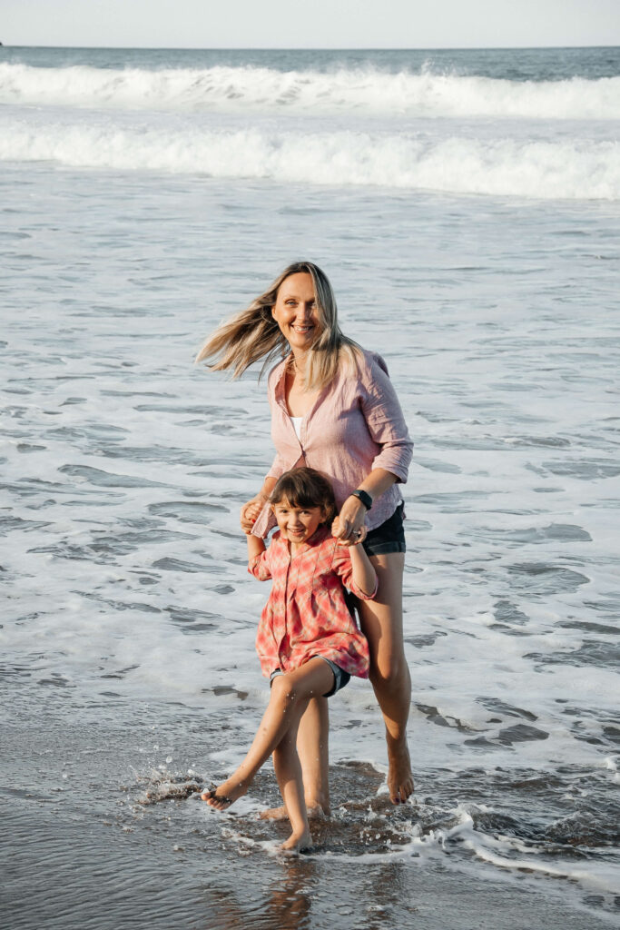 Mother and child walking along Hot Water Beach shoreline