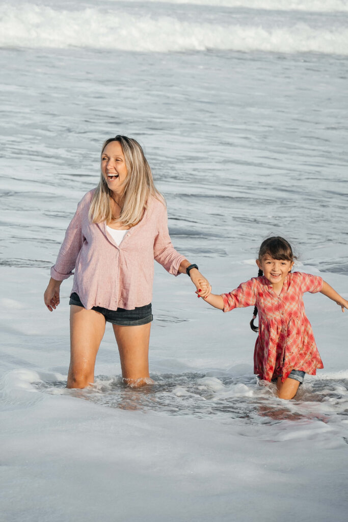 Mother and child walking along Hot Water Beach shoreline