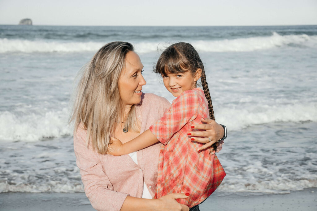 Mother holding daughter during golden hour at Hot Water Beach