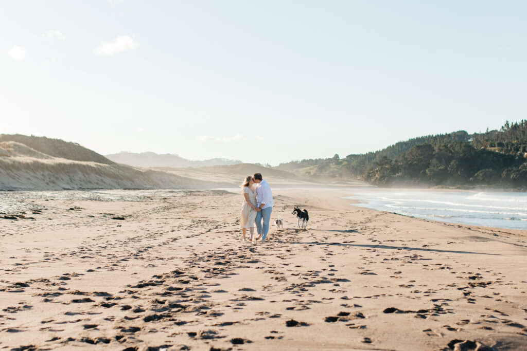 Dogs running along the sand during engagement session at Hot Water Beach