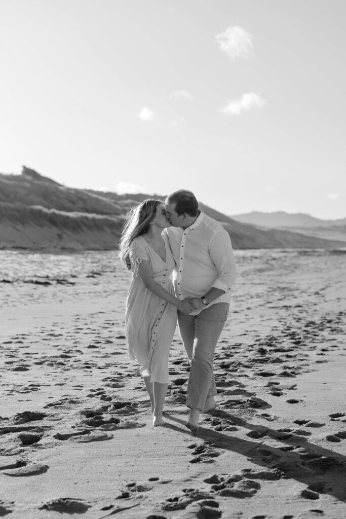 Couple holding hands during golden hour at Hot Water Beach Coromandel