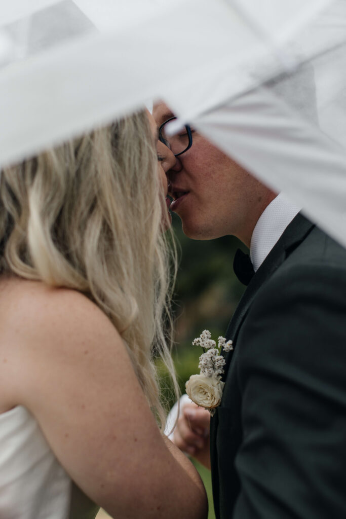 Bride and groom kissing under umbrella at Puketutu Island Estate Auckland