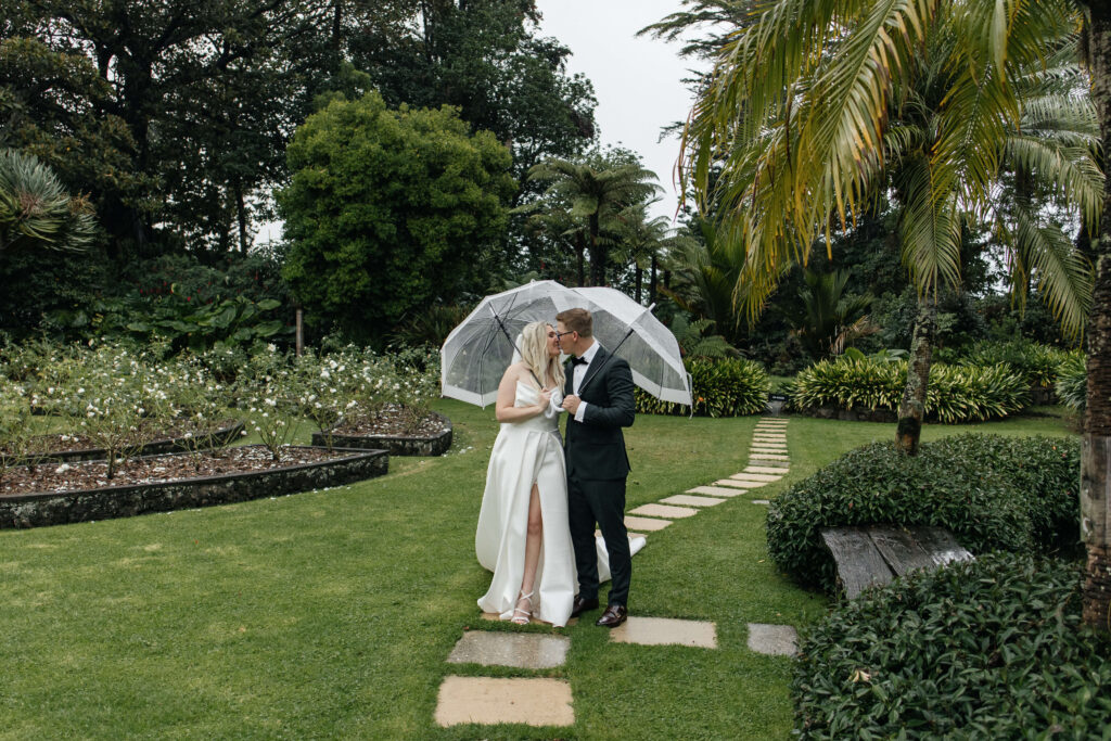 Bride and groom kissing under umbrella at Puketutu Island Estate Auckland