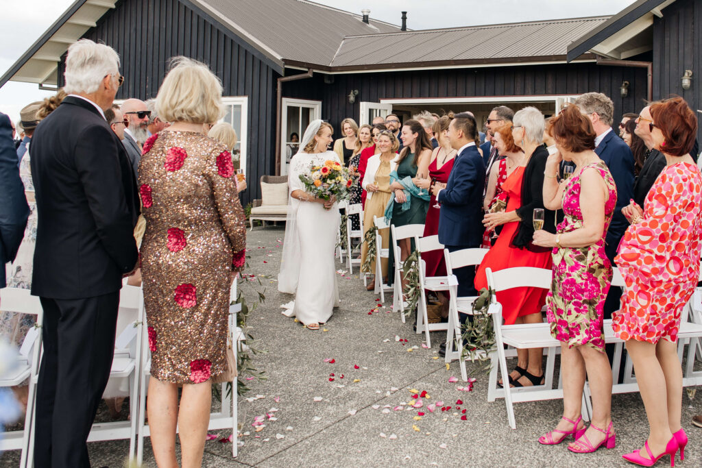 Bride is walking down the aisle during the wedding at Mudbrick Lodge