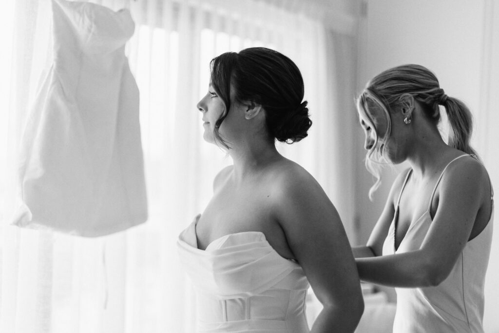 Bride is putting her dress on her wedding day at Castaways Resort in Waiuku