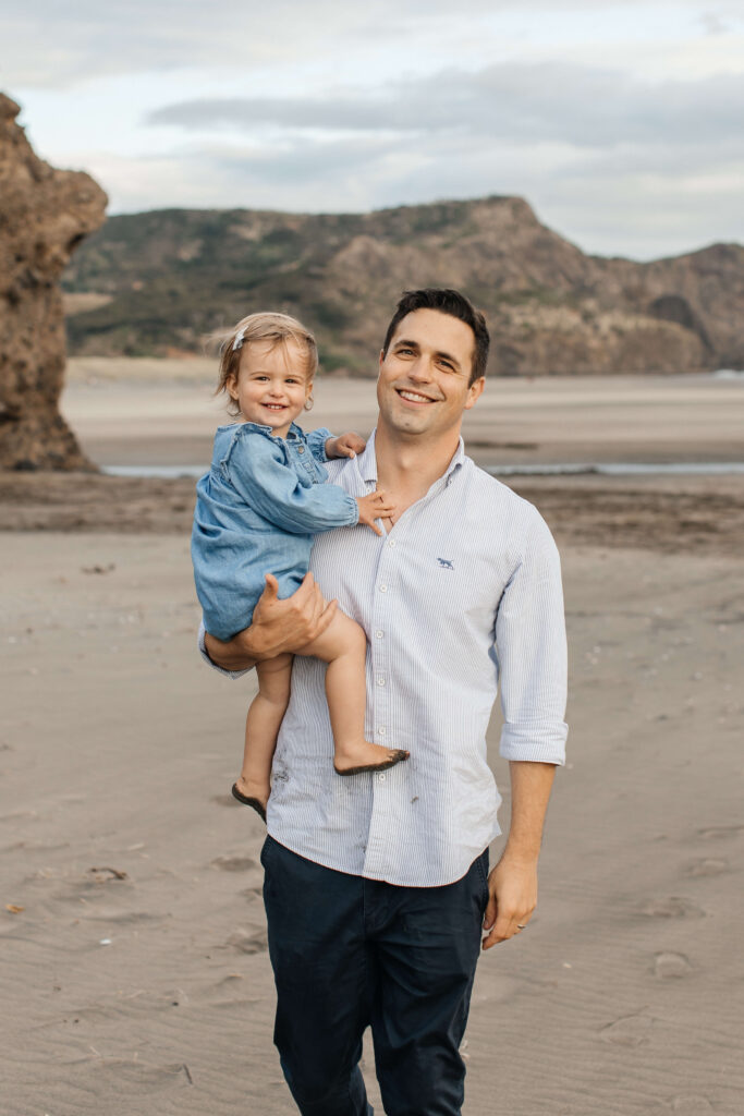 Dad carrying little girl with ocean in the background