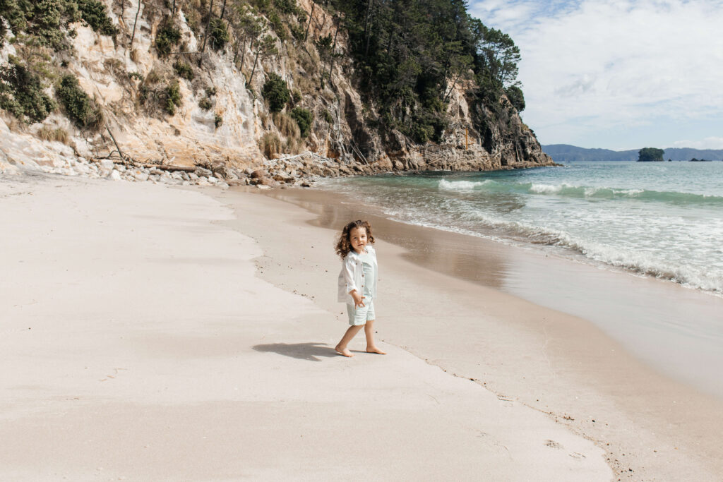 Little girl playing in the sand at Hahei Beach during family photo session