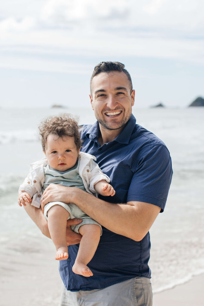 Canadian mum and dad holding their young children during Hahei Beach family portraits