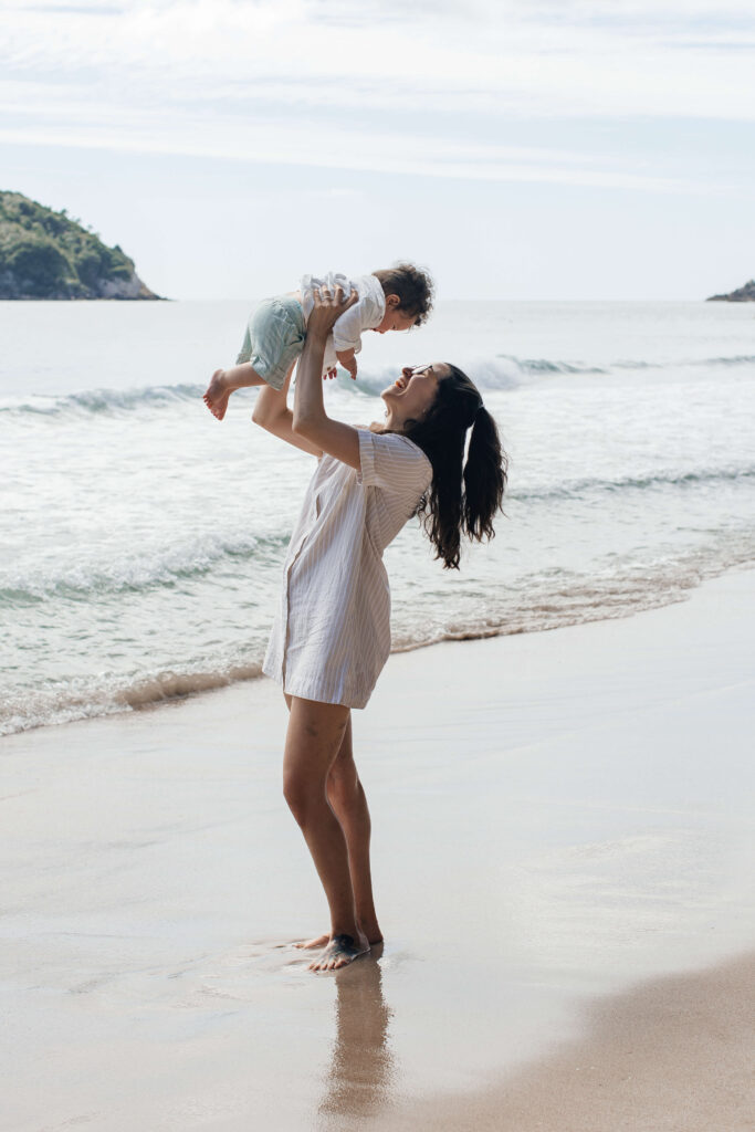 Canadian mum and dad holding their young children during Hahei Beach family portraits