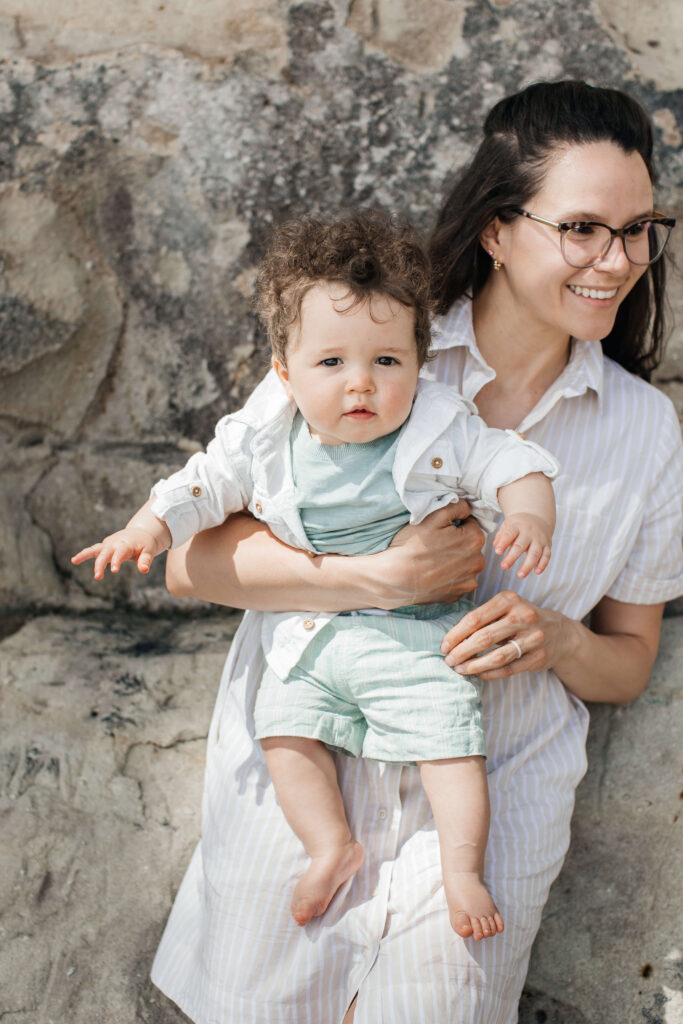 Baby boy smiling while being held by his mum during Hahei Beach family photos