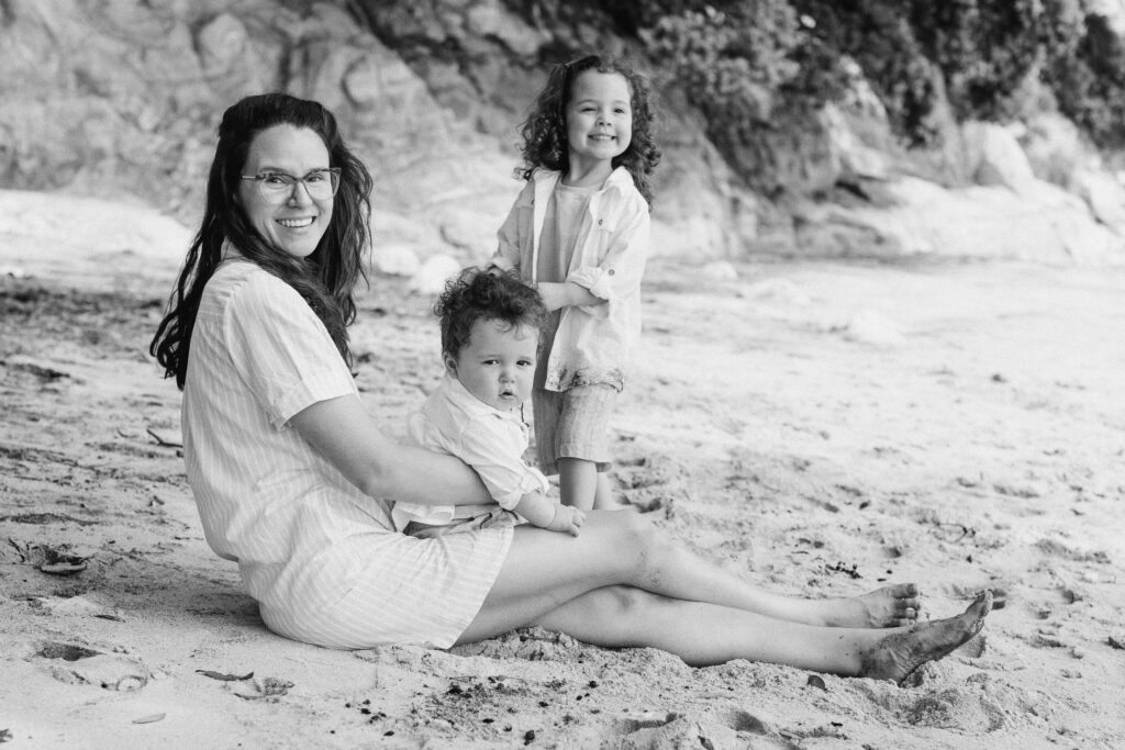 Baby boy smiling while being held by his mum during Hahei Beach family photos