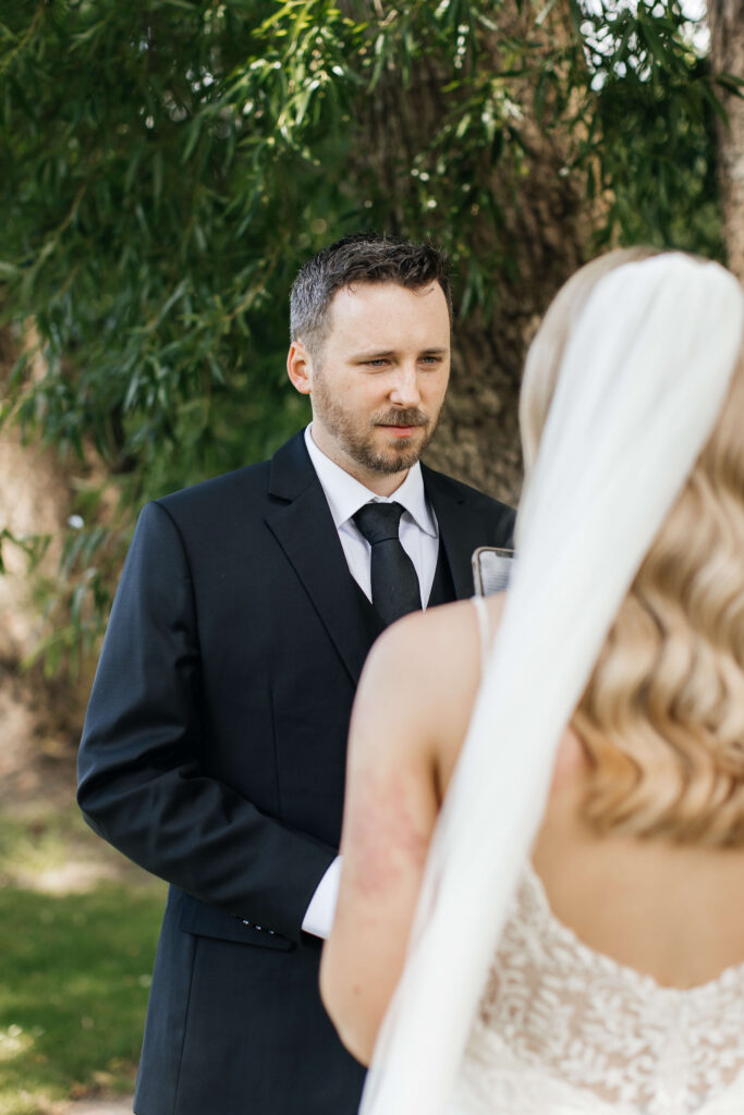 Shay and Howerd sharing private vows in the gardens at Abel Estate, captured candidly by their Auckland wedding photographer.