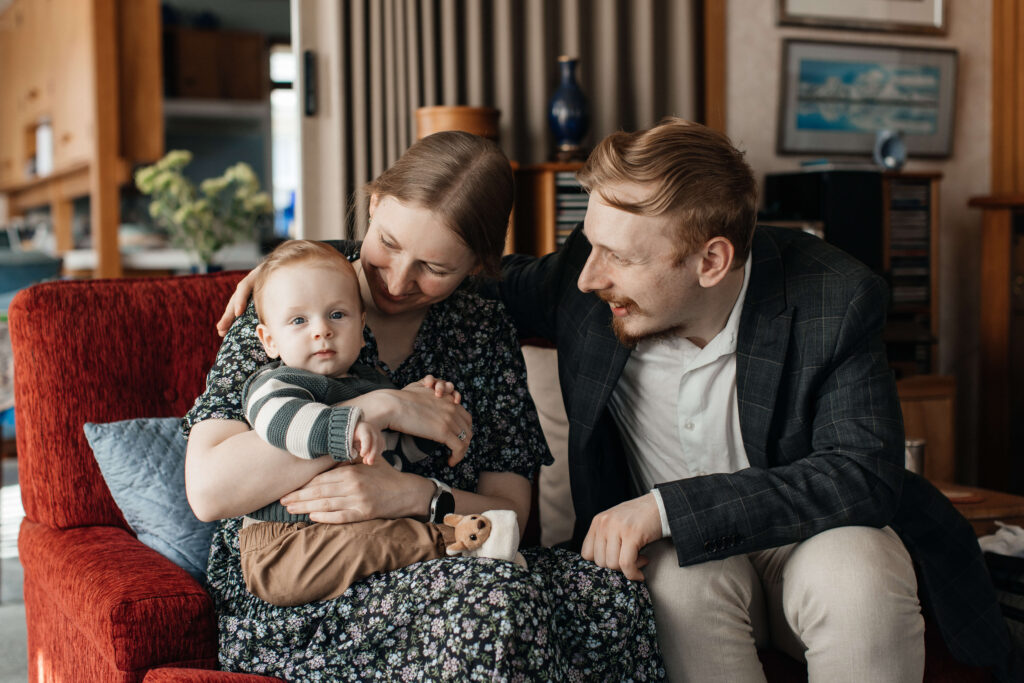 Mum, dad, and little son cuddling together on the couch during their relaxed family photo session at home.