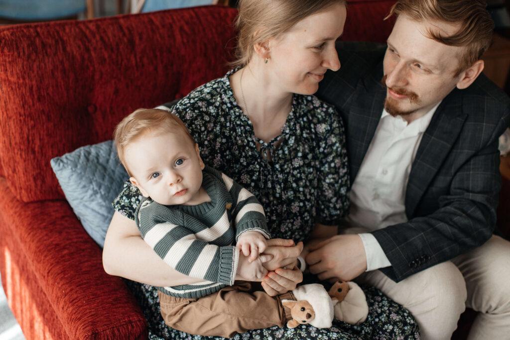 Mum, dad, and little son cuddling together on the couch during their relaxed family photo session at home.