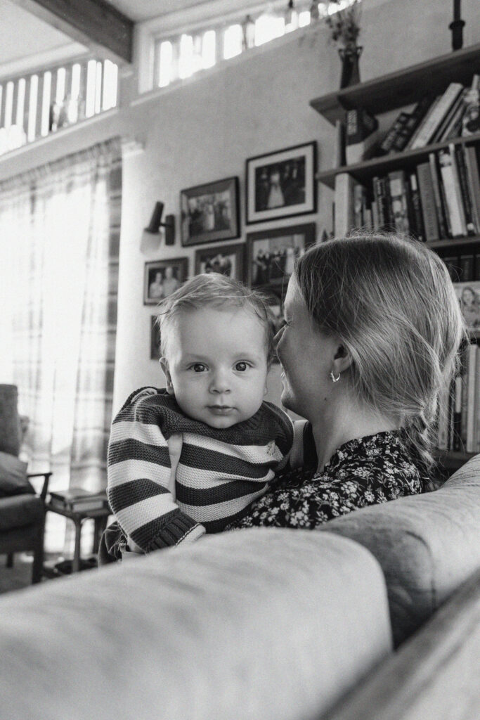 Parents laughing while playing with their young son in the living room during an at-home lifestyle family photoshoot.
