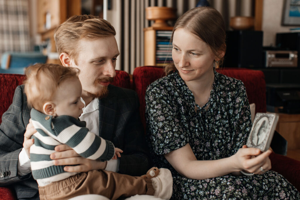 Mum, dad, and little son cuddling together on the couch during their relaxed family photo session at home.
