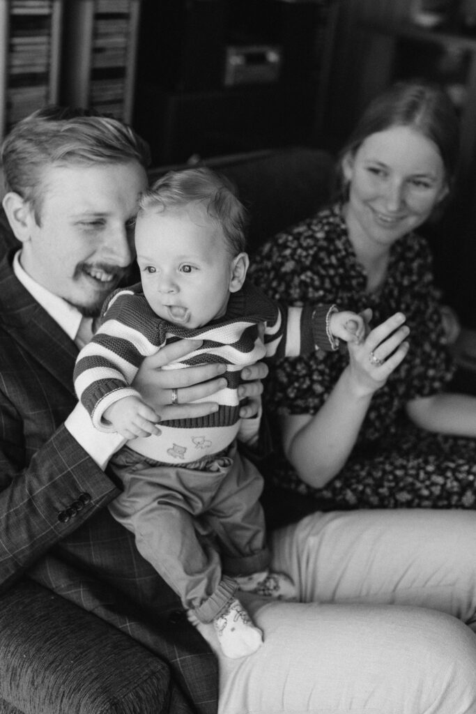 Mum, dad, and little son cuddling together on the couch during their relaxed family photo session at home.