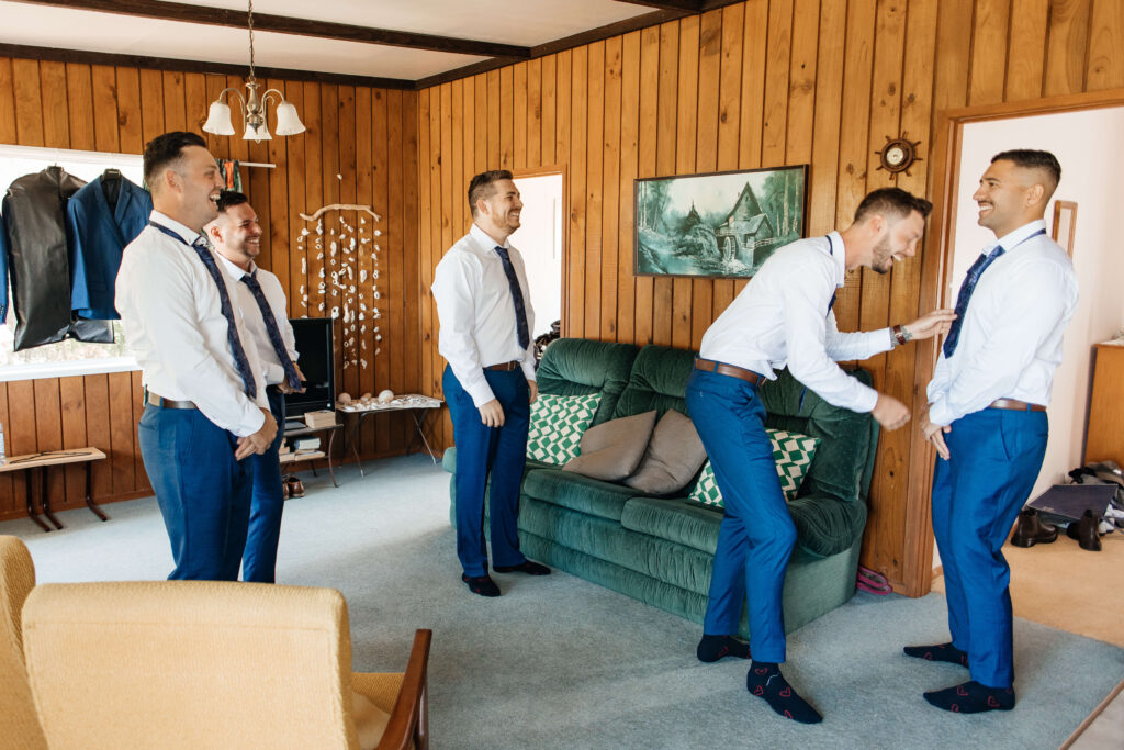 Groom preparing for Old Forest School wedding day in Pukehina with estuary views.