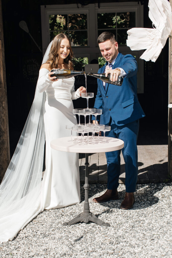 Bride and groom pouring champagne tower at Old Forest School wedding reception.