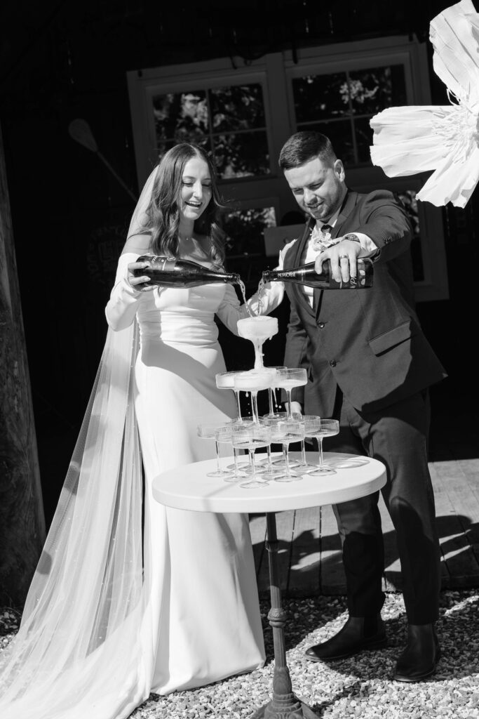 Bride and groom pouring champagne tower at Old Forest School wedding reception.