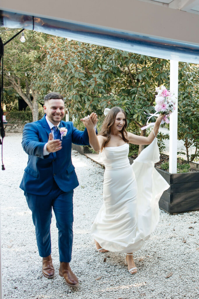 Bride and groom entering Old Forest School wedding reception to cheers and applause.