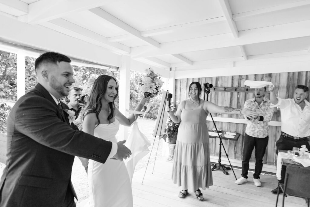 Bride and groom entering Old Forest School wedding reception to cheers and applause.